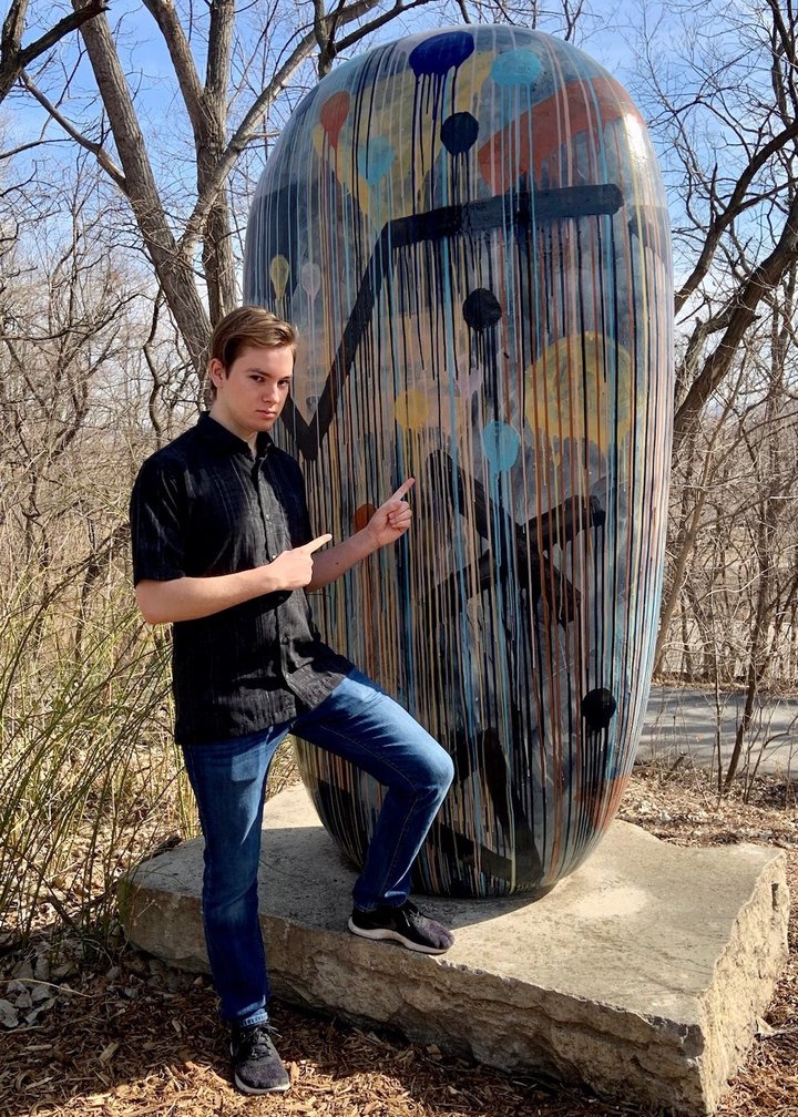 Luke Marzen standing in front of a giant bean painted with mathematical symbols.